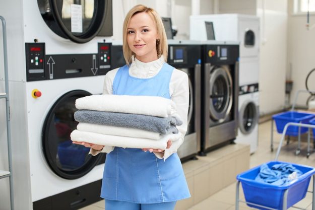 3 Benefits of Laundry Services for Seniors a woman in a laundry room working in laundry services for seniors