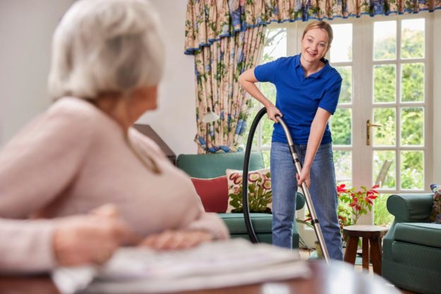 Finding the Right Housekeeping For Seniors woman with vacuum talking to a senior in housekeeping for seniors