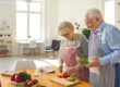 two older people cooking a meal at home together