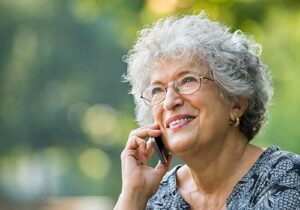 elderly woman smiling while talking on the phone